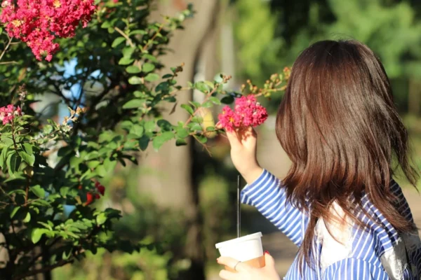 a young girl holding a cup of coffee and smelling flowers