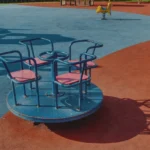2 black metal framed red padded armchairs on brown sand near body of water during daytime