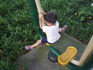 A child enjoys playing on outdoor fitness equipment.