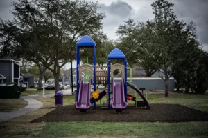 A colorful playground with two slides and trees.